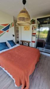 a bedroom with a bed with a red blanket at Tiny house ''De Veenpolder'' in De Veenhoop