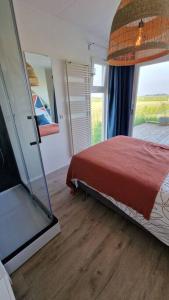 a bedroom with a bed and a window and a television at Tiny house ''De Veenpolder'' in De Veenhoop