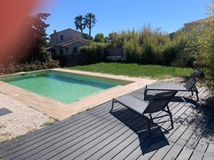 une terrasse avec une piscine, une table et un banc dans l'établissement Magnifique Villa idéalement située, à Puget-sur Argens