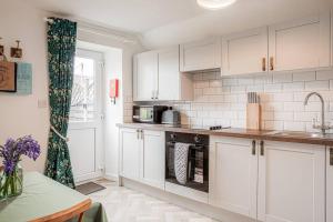 una cocina con armarios blancos y fregadero en Light and Central Apartment above Knead Bakery, en Tetbury