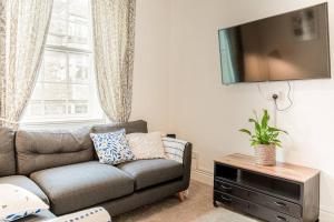 a living room with a couch and a flat screen tv at Light and Central Apartment above Knead Bakery in Tetbury