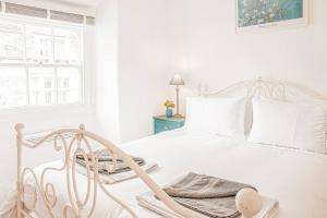 a white bedroom with a white bed and a window at Light and Central Apartment above Knead Bakery in Tetbury