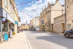 a street in an old town with flags and buildings at Light and Central Apartment above Knead Bakery in Tetbury