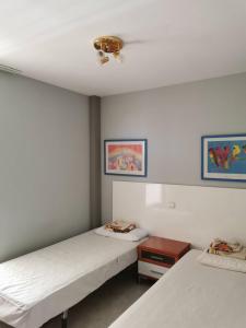 Cette chambre comprend 2 lits et une table. dans l'établissement Family Sun Seasight Apartment, à Cala Millor