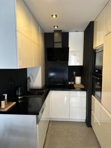 Una cocina con gabinetes blancos y encimeras negras. en Apartament Komfort, en Zamość
