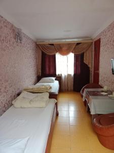 a small room with two beds and a table at Гостиница Энглер в Хромтау in Khromtaū
