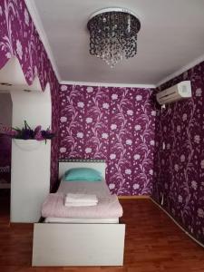 a bedroom with purple walls and a bed with a chandelier at Гостиница Энглер в Хромтау in Khromtaū