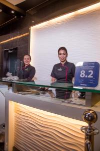 two men standing behind a glass counter with a clock at Y2 Residence Hotel Managed by HII in Manila