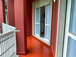 a hallway with two windows and a red wall at Bnbook Lattuada 3 camere da letto 2 bagni in Rho