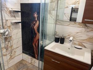 a bathroom with a sink and a shower with a woman painted on the wall at Panoramic apartment in Varna with underground parking in Varna City +38 photos