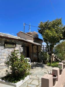 una casa de piedra con un árbol y un edificio en Double studio room in Mylopotamos with beautifull view, en Tsagkarada