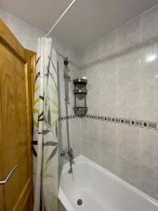 La salle de bains est pourvue d'une baignoire blanche et d'une douche. dans l'établissement Apartment Goya, à Torrevieja