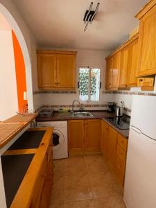 kuchnia z drewnianymi szafkami i białą lodówką w obiekcie Apartment Goya w mieście Torrevieja