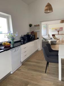 a kitchen with white cabinets and a living room at Quinta da Layla in Olhão