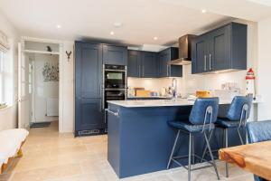 a kitchen with blue cabinets and blue bar stools at Lobster Cottage in Poole
