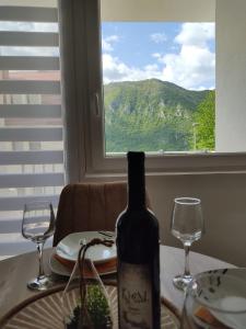 a bottle of wine sitting on a table with two glasses at Apartman Andjela in Pluzine