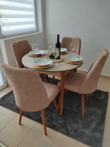 einen Esstisch mit Stühlen und eine Flasche Wein in der Unterkunft Apartman Andjela in Plužine