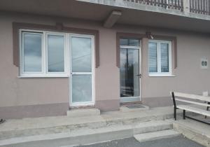un banc installé à l'extérieur d'une maison avec fenêtres dans l'établissement Apartman Đoladuma, à Gacko