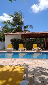 - deux chaises jaunes installées à côté de la piscine dans l'établissement Pousada Vila Caju, à São Miguel do Gostoso