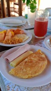 uma mesa com pratos de alimentos para o pequeno almoço e uma bebida em Pousada Vila Caju em São Miguel do Gostoso