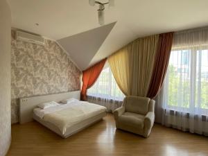 a bedroom with a bed and a chair and windows at Parus in Chernivtsi