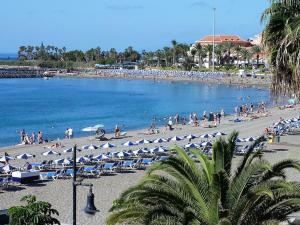 grupa ludzi na plaży z leżakami i parasolami w obiekcie estudio Los Cristianos-Tenerife- w mieście Los Cristianos