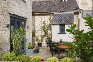 a patio with a table and chairs in front of a building at A beautiful Georgian town house in Painswick in Painswick