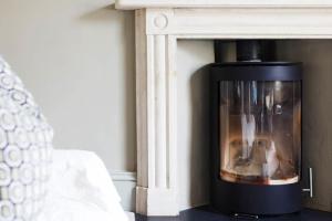 a fireplace in a living room next to a bed at A beautiful Georgian town house in Painswick in Painswick