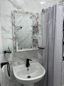 een witte badkamer met een wastafel en een spiegel bij Guest House SAMAN in Garni