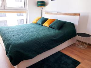uma cama com um edredão verde num quarto em Fachpol Apartments Sienkiewicza 22D em Zamość