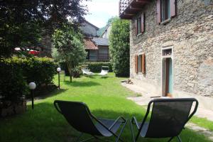 two chairs sitting in the yard of a house at Apartment Bianca with private garden in Cossogno