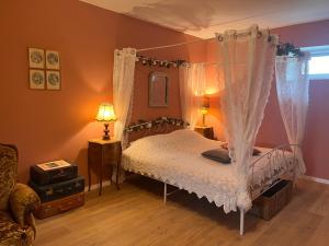 een slaapkamer met een hemelbed en witte gordijnen bij Gîte "La Brocante" in Chamblet