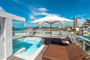 a balcony with a swimming pool and an umbrella at DELUX PRAIA Flats in Natal