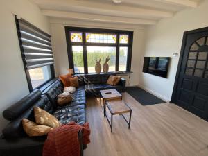 a living room with a black leather couch and a table at The island life beach house 1 in De Koog