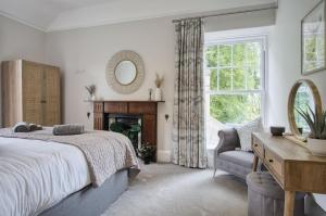 a bedroom with a bed and a mirror and a chair at Hill House Country Estate - Princes Gate in Ludchurch