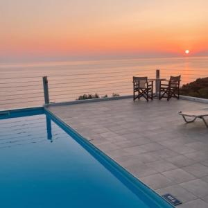 a pool with a table and chairs and the sunset at Kapetaniou Apartments in Limnionas