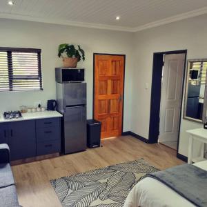 a kitchen with a sink and a refrigerator in a room at Palm On Rock - 1 bedroom,kitchenette & full bathroom. in Bloemfontein