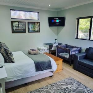 a bedroom with a bed and a couch and a television at Palm On Rock - 1 bedroom,kitchenette & full bathroom. in Bloemfontein