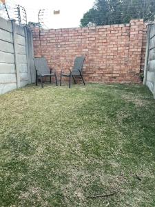 two chairs sitting in a yard next to a brick wall at Side Step in Johannesburg