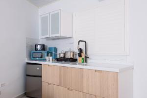 a white kitchen with a sink and a microwave at Irenestraat 23 in Oranjestad