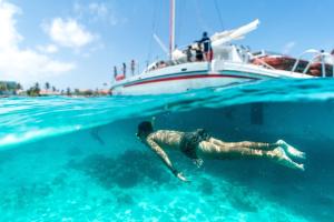 a man swimming in the water next to a boat at Irenestraat 23 in Oranjestad