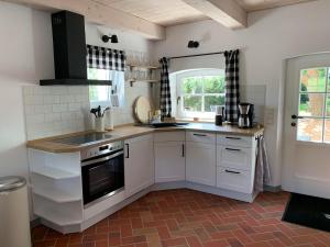 a kitchen with white cabinets and a sink and a window at Hygge-Huus-Burhave in Burhave