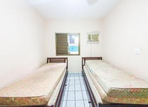 two beds in a room with a window at Paraiso do Sol in Ubatuba