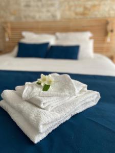 ein weißes Handtuch mit einer Blume auf dem Bett in der Unterkunft Au cocon de Bélice in Benon