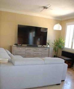 ein Wohnzimmer mit einem weißen Sofa und einem Flachbildfernseher in der Unterkunft La villa castellas in Carpentras