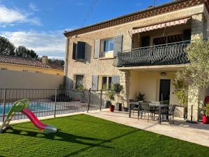 ein Haus mit Rasen und Rutsche im Hof in der Unterkunft La villa castellas in Carpentras