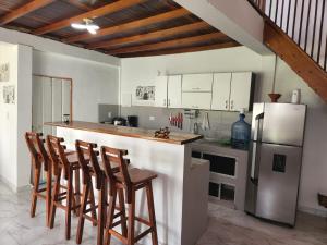 a kitchen with a bar with chairs and a refrigerator at Villa Mimosa Finca Hotel in Quimbaya