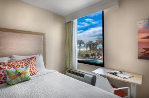 a bedroom with a bed and a desk and a window at Surfside Beach Oceanfront Hotel in Myrtle Beach