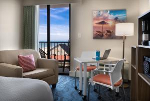 a hotel room with a bed and a desk and a table at Surfside Beach Oceanfront Hotel in Myrtle Beach