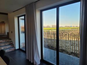 ウータウにあるIn de Voorstad Watouのグラスのスライドドアから野原の景色を望む客室です。